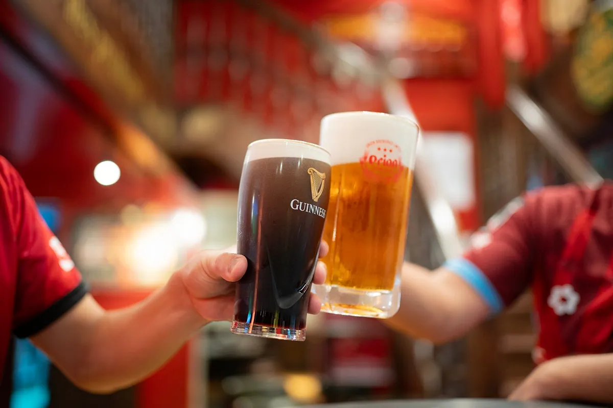 ギネスとビールのグラスで乾杯する2人