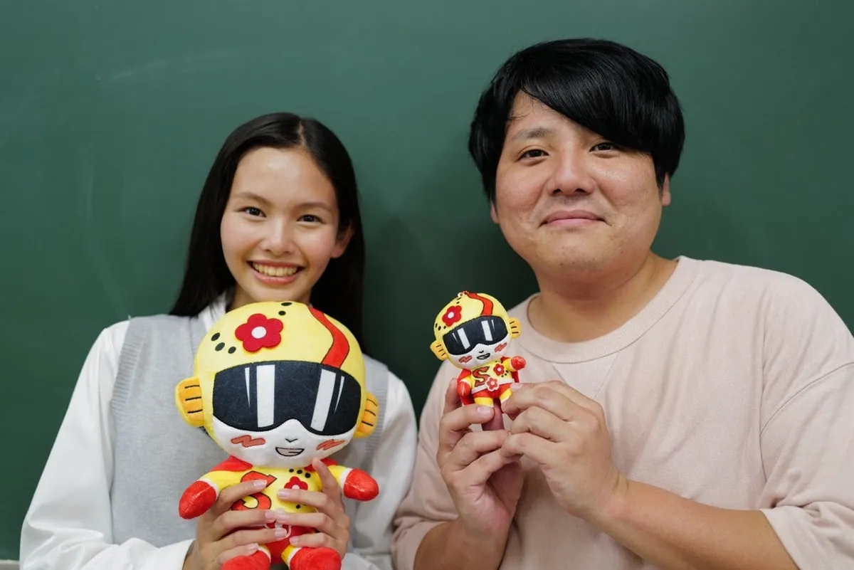 スッパイマンの人形を持って並ぶ2人