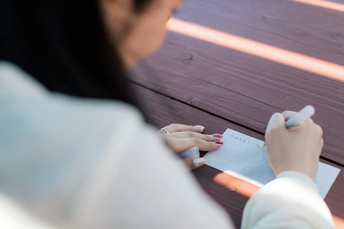 テーブルで手紙を書く人の手元